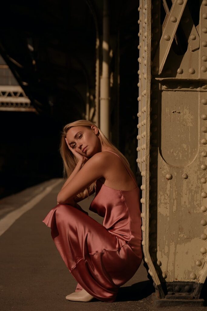 woman in pink spaghetti strap dress sitting on sidewalk